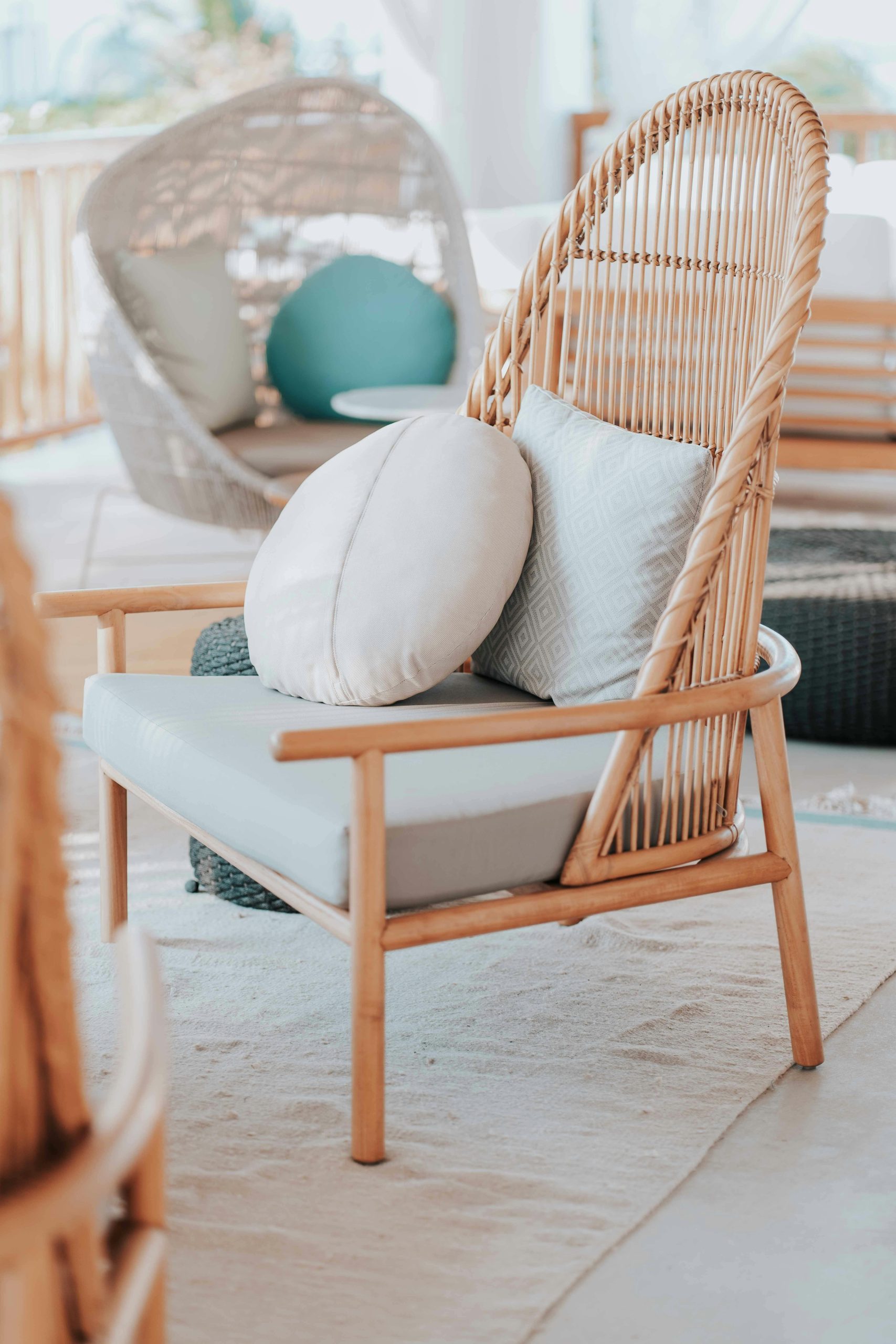 Home Cozy wicker chair with soft cushions in an inviting outdoor setting for relaxation.