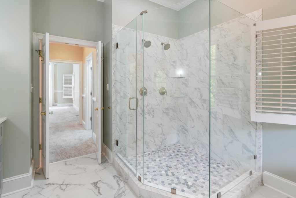 Spacious luxury bathroom featuring a contemporary marble shower with glass doors and elegant interior design.